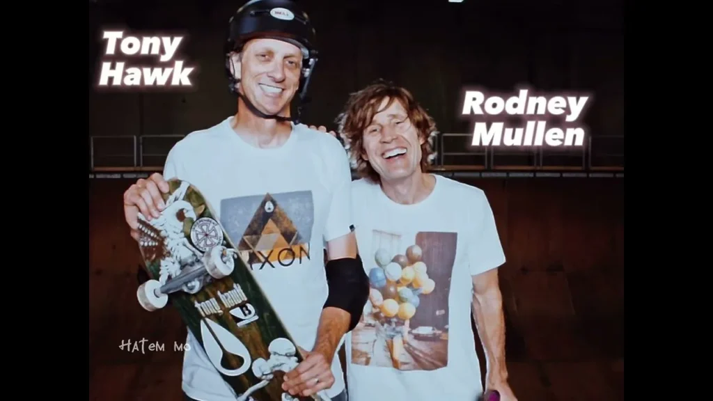 Fotografia storica di due protagonisti della Bones Brigade con skateboard, accompagnata dai nomi Tony Hawk e Rodney Mullen.