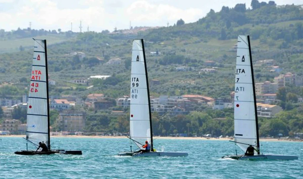 Tre catamarani Classe A con vele alte navigano lungo la costa di Vasto Marina