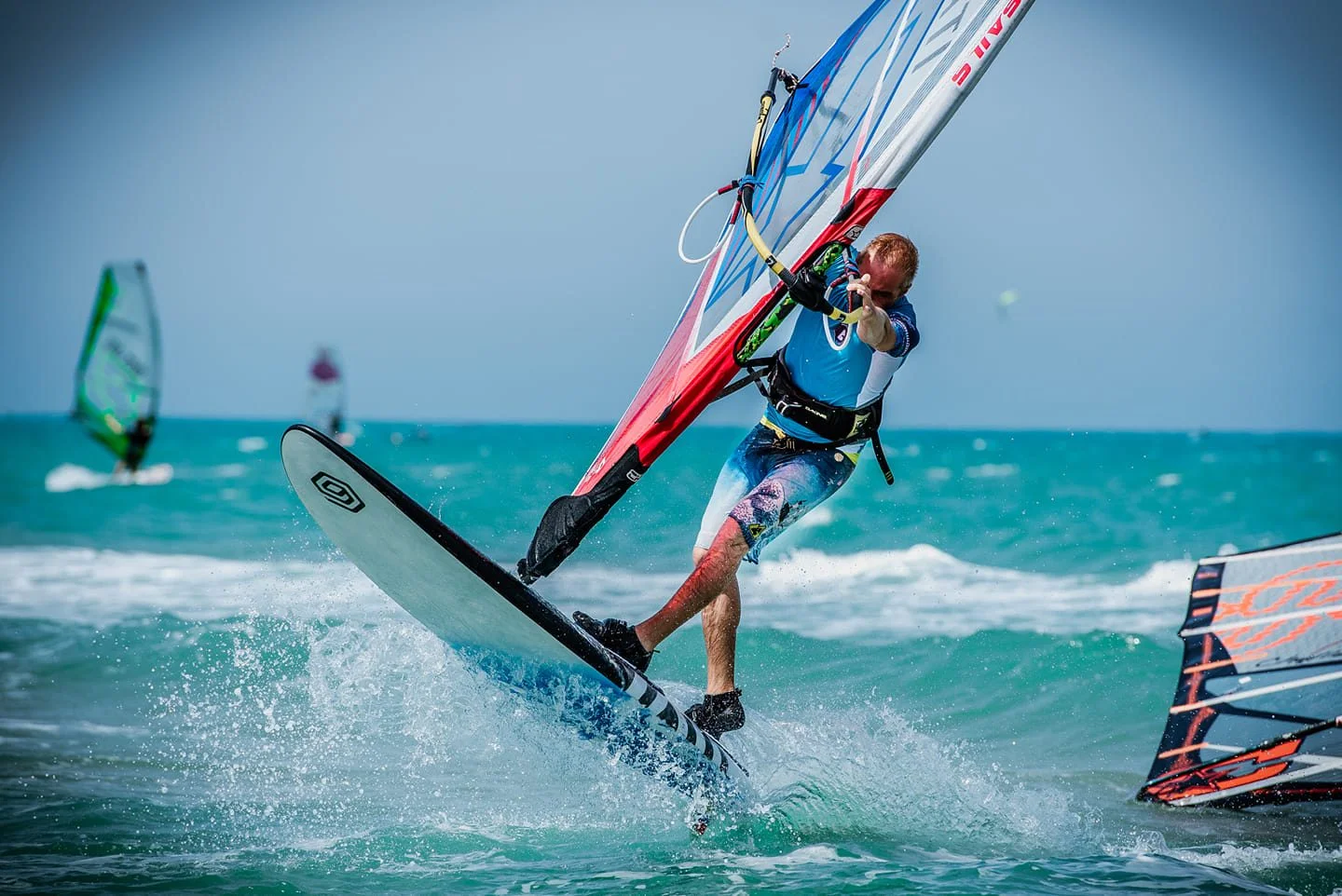 Praticanti di windsurf con tavola e vela in acqua