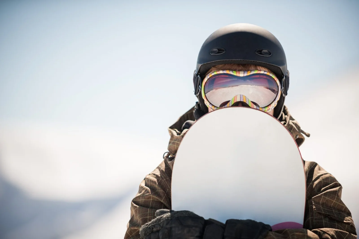 Snowboarder con casco e tavola sulla neve per il corso Snowboard Coach CSEN