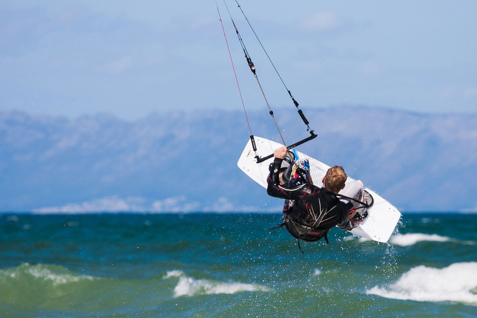 Kitesurfer in salto con tavola e kite sul mare