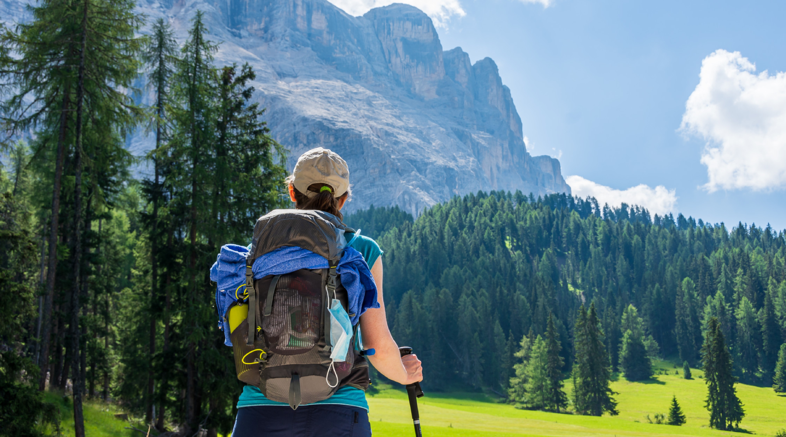 Escursionista con zaino e bastoncino davanti a un paesaggio montano